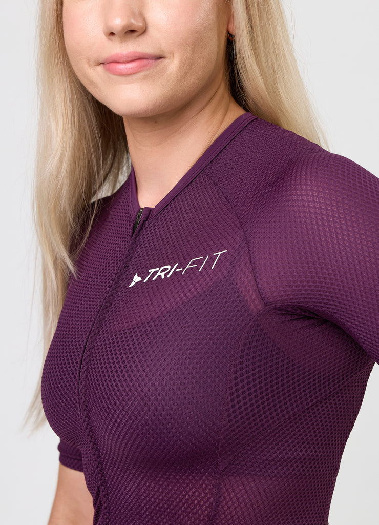 Close-up of TRI-FIT logo printed on the chest of the VANGUARD tri-suit in plum, showing textured breathable fabric