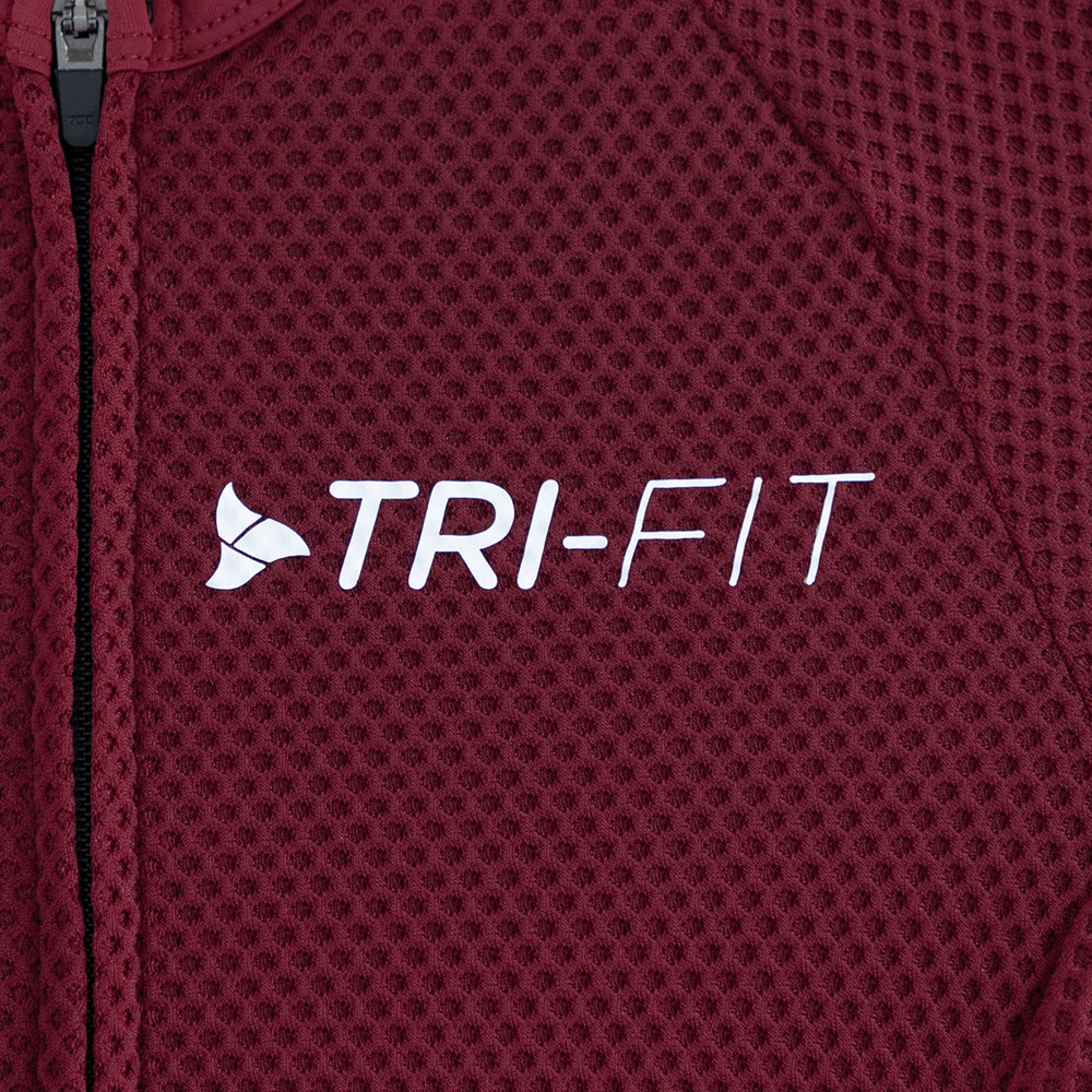 Close-up of TRI-FIT logo printed on the chest of the VANGUARD tri-suit in wine red, showing textured breathable fabric